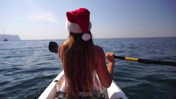 Jeune attrayant brunette femme avec longue cheveux dans blanc maillot de bain, nager sur kayak autour volcanique rochers, comme dans Islande. retour voir. Noël vacances vacances et Voyage concept. video