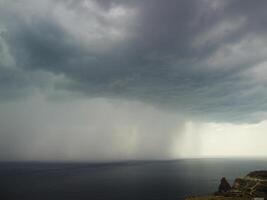 Aerial view footage of rain clouds over sea ocean Black clouds in bad weather day over sea surface High angle view nature view. Apocalypse. Storm Large freight dark gloomy rain clouds over a calm sea. photo