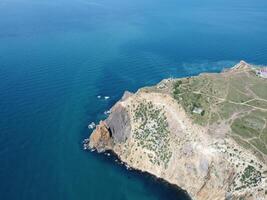 Aerial view from above on calm azure sea and volcanic rocky shores. Small waves on water surface in motion blur. Nature summer ocean sea beach background. Nobody. Holiday, vacation and travel concept photo