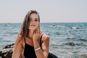 mujer verano viaje mar. contento turista en sombrero disfrutar tomando imagen al aire libre para recuerdos. mujer viajero posando en el playa a mar rodeado por volcánico montañas, compartiendo viaje aventuras viaje foto