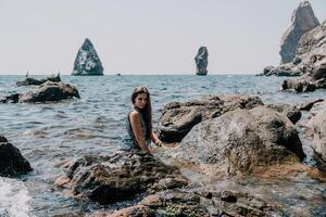 mujer verano viaje mar. contento turista disfrutar tomando imagen al aire libre para recuerdos. mujer viajero posando en el playa a mar rodeado por volcánico montañas, compartiendo viaje aventuras viaje foto