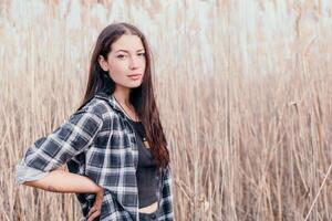 contento joven sonriente mujer con pecas al aire libre retrato. suave soleado colores. al aire libre de cerca retrato de un joven morena mujer y mirando a el cámara, posando en contra otoño naturaleza antecedentes foto