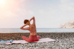 mujer mar pilates deportivo contento medio Envejecido mujer practicando aptitud en playa cerca mar, sonriente activo hembra formación con anillo en yoga estera afuera, disfrutando sano estilo de vida, armonía y meditación foto