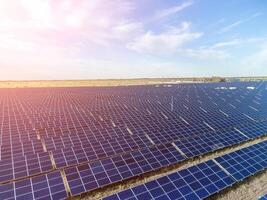 Aerial top view of a solar panels power plant. Photovoltaic solar panels at sunrise and sunset in countryside from above. Modern technology, climate care, earth saving, renewable energy concept. photo