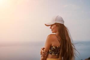 Woman travel sea. Happy tourist taking picture outdoors for memories. Woman traveler looks at the edge of the cliff on the sea bay of mountains, sharing travel adventure journey photo