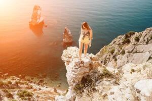 Woman travel sea. Happy tourist enjoy taking picture outdoors for memories. Woman traveler looks at the edge of the cliff on the sea bay of mountains, sharing travel adventure journey photo