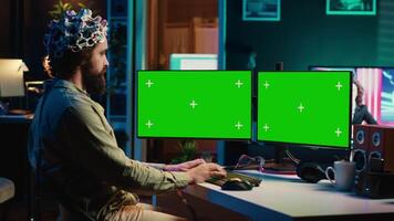 Computer engineer using EEG headset, starting mind upload process using green screen PC. Man using neuroscientific device to transfer consciousness into cyberspace with mockup monitors, camera A video