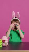 lächelnd süß Kind spielen spähen ein Boo Spiel mit gemalt bunt Eier, haben Spaß mit Ostern Dekorationen und Vereinbarungen auf Kamera. begeistert froh Junge Sein aufgeregt Über Urlaub. Kamera b. video