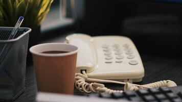 kop van koffie en papierwerk Aan kantoor bureau met bedrijf winst analyse, dichtbij omhoog schot. bedrijf documenten, heet drank en telefoon Aan tafel in accounting werkplaats video