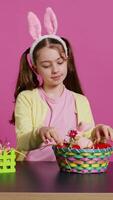 Sleepy little girl yawning while she arranges easter eggs for festive decorations, almost falling asleep at the table where she decorates for spring holiday celebration. Tired schoolgirl. Camera B video