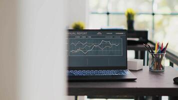 o negócio gráficos e figuras em computador portátil esquerda aberto em escrivaninha dentro esvaziar área de trabalho. econômico anual relatório gráficos em caderno tela dentro companhia financeiro departamento escritório, panning tiro video