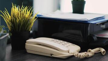 companhia papelada em topo do impressora, Telefone e mini casa plantas em escritório escrivaninha fechar acima. o negócio documentos, impressão máquina e telefone em mesa dentro contabilidade local de trabalho video