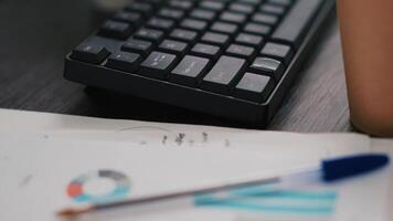 Computer keyboard and business graphs and figures on paperwork files showing profits. Economic annual report charts on paper documents in company financial department office, close up shot video