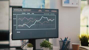 Business graphs and figures on computer monitor left open in empty workspace. Economic annual report charts on PC desktop screen in company financial department office, close up shot video