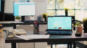 Stock market diagrams with charts and stock figures on laptop showing profits, empty workspace. Trading index listings displayed on notebook screen in office, panning shot video