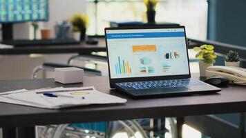 Inclusive office with wheelchair in blurry background and notebook in foreground showing marketing report. Workspace offering accessibility for workers and laptop with business analytics, panning shot video