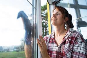 Woman manually washes the window of the house with a rag with spray cleaner and mop inside the interior with white curtains. Restoring order and cleanliness in the spring, cleaning servise photo