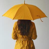 AI generated Girl with yellow umbrella on white background with her back turned to the camera. Girl holding umbrella in front of a background. Person under umbrella photo