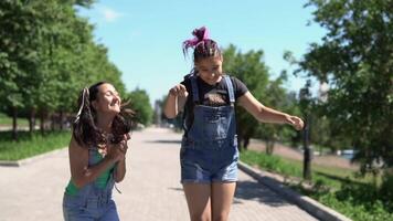 dois lindo amigas amigas com grandes cabelo estão feliz e saltar dentro a parque dentro ensolarado clima. lento movimento video