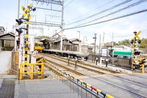 Perspective view of Nara local train was leaving the Nara train station and going through a road under bright blue sky. photo