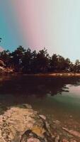 A lake surrounded by trees and rocks under a cloudy sky video