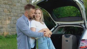 glücklich Paar Reisen durch Wagen. Mann und Frau umarmen in der Nähe von das Wagen. aktiv Freizeit zum jung Menschen video