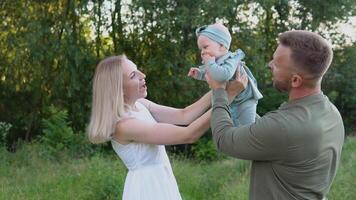 gelukkig paar Toneelstukken met baby dochter Aan gazon in park. gelukkig familie resting in de park video