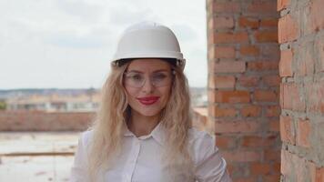 Female architect in business attire and a white helmet stands at the construction site video