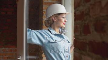 vrouw architect op zoek uit de venster Bij een bouw plaats. de werkwijze van gebouw behuizing voor de familie video