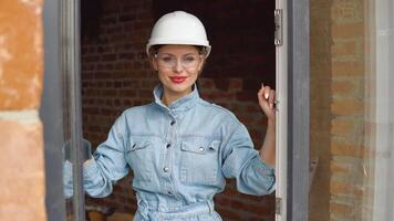 A female architect or bricklayer stands in an open window at a construction site. The process of building housing for the family video