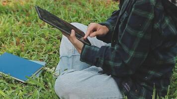 gruppo di contento giovane asiatico Università studenti seduta su un' panca, guardare a un' il computer portatile schermo, discutere e di brainstorming su loro scuola progetto insieme. video