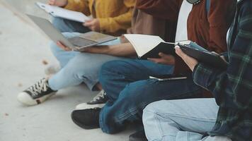 Group of happy young Asian college students sitting on a bench, looking at a laptop screen, discussing and brainstorming on their school project together. video