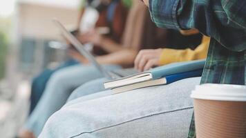 gruppo di contento giovane asiatico Università studenti seduta su un' panca, guardare a un' il computer portatile schermo, discutere e di brainstorming su loro scuola progetto insieme. video