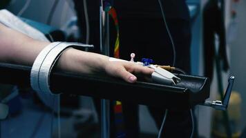 Patient's hand under anesthesia in the operating room, a pulse oximeter on the finger. The patient lies on a hospital bed in the operating room. Modern medical technologies, surgery video