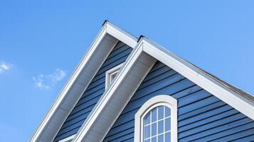 AI generated The top roof and gable on a blue house with white trim, against a blue sky background. photo