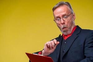 Middle aged businessman standing and holding file folder. Horizontal format isolated on yellow background. photo