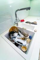 Dirty messy dishes in a sink. View from above. Clean up concept. photo