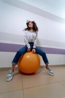 mujer sentado en aptitud pelota y saltando ejercicios para abdominales, piernas y atrás. sano vida estilo. foto