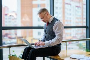 Side view on man with laptop on knees. Working manager. Neatly weared man in suit. photo