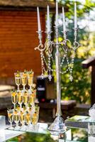 Vertical stand of champagne in the glasses. Candelstick with pearl thread. Nice tender decoration. Celebration in summer. photo