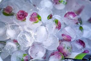 Flowers frozen in balls made of ice at holiday. Fashion table decoration. Delicate lilac flowers in ice. Closeup. photo