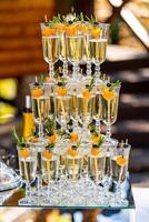 Champagne in the glasses against the wooden background. Vertical stand of glasses. Close up. photo