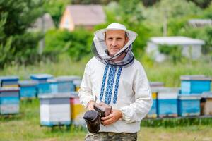 Male beekeeper over hives background. Protective hat. Blurred background. Honey and bees. photo