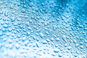 Rain drops on the window. Blue tone on the background. Many water drops on glass. photo