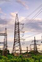 Electricity pylons and high-voltage power lines on the green grass. Power plant. Electrical power grid. View from below. photo