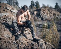 Heavy training in a quarry. Intense workout. Strong attractive bodybuilder. Lifestyle. White landscape. photo