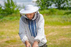 Beekeeper at apiary at the summer day. Man working in apiary. Apiculture. Beekeeping concept. photo