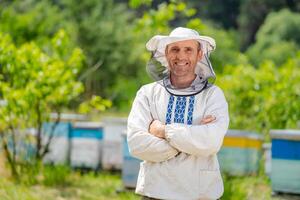 The beekeeper stands crosshands near apiary. Apiculture. Apiary. photo