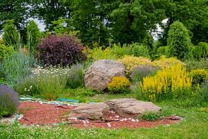 Alpine hill with lush green grass. Lawn and winding pathway in a beautiful english style garden. photo