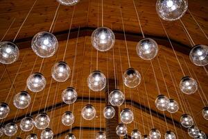Lamps hanging on celling. Wood background. Warm light. Modern design. View from below. photo